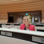Auf dem Foto ist Julia Moser, Geschäftsführerin in Österreich zu sehen, während sie in ein Mikrofon spricht.