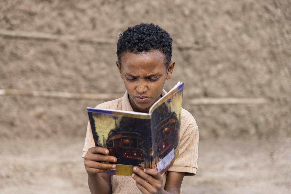 Auf dem Bild ist der 12-jährige Zecharias zu sehen. Er zeigt erste Anzeichen einer Trachomerkrankung und versucht angestrengt eine Zeitschrift zu lesen.