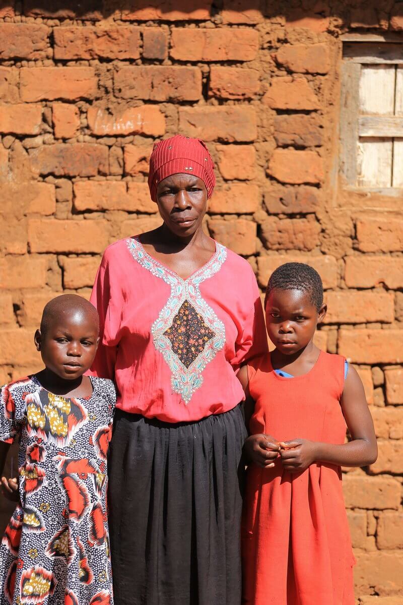 Auf dem Bild sind die siebenjährige Nuubu, die neunjährige Fahira und ihre Großmutter Nuubu zu sehen. Sie leben gemeinsam in dem Dorf Kikubo in Uganda.
