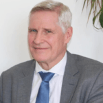 Herr Dr. Prayer gibt Tipps zu Testament und Vermächtnis. Er trägt einen grauen Anzug mit blauer Krawatte.