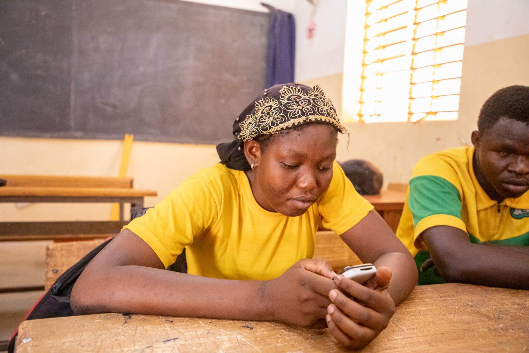 Minata aus Burkina Faso ist blind und hält ihr Audiogerät in den Händen. Mit ihm kann sie Klassen aufzeichnen und Bücher anhören.