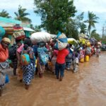 Auf dem Bild sind zahlreiche Menschen zu sehen, die nach einem Zyklon in Mosambik mit all ihren Habseligkeiten flüchten.