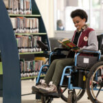 The image shows a woman in a wheelchair reading a book in a library. The CapAble project, which puts disability inclusion into action in higher education, has won a Zero Project Award.