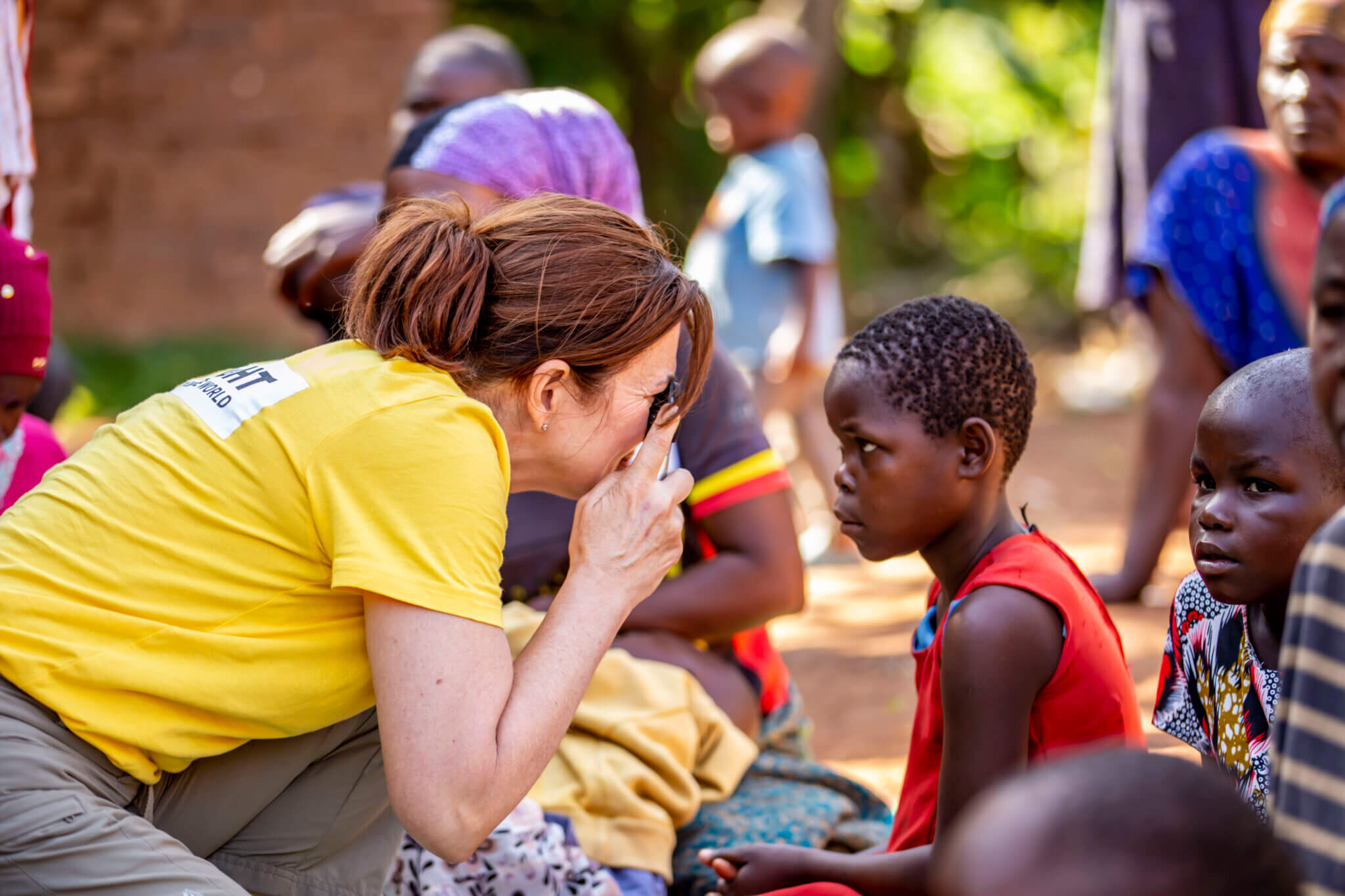 Auf dem Bild ist eine Augenärztin in Uganda zu sehen. Sie ist mit der Hilfsorganisation Licht für die Welt vor Ort in einem Dorf, um die Menschen dort zu untersuchen. Gerade untersucht sie ein junges Mädchen, das wegen Grauem Star operiert wurde.