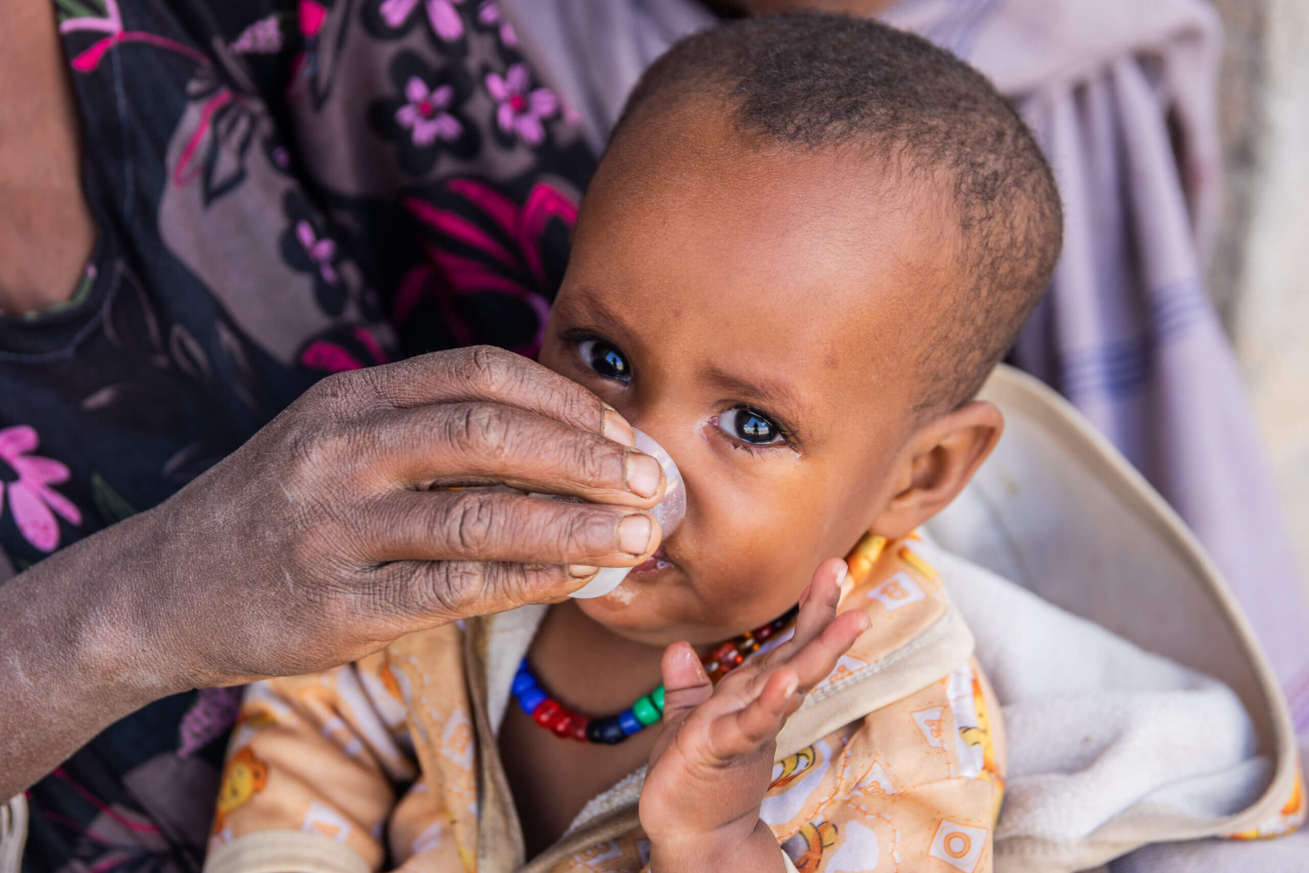 Einjähriges Mädchen bekommt ein Antibiotika gegen die Infektionskrankheit Trachom in flüssiger Form in einem kleinen Becher verabreicht