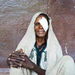 Eine ältere Frau aus Äthiopien, die gerade operiert wurde, blickt lächelnd in die Kamera.