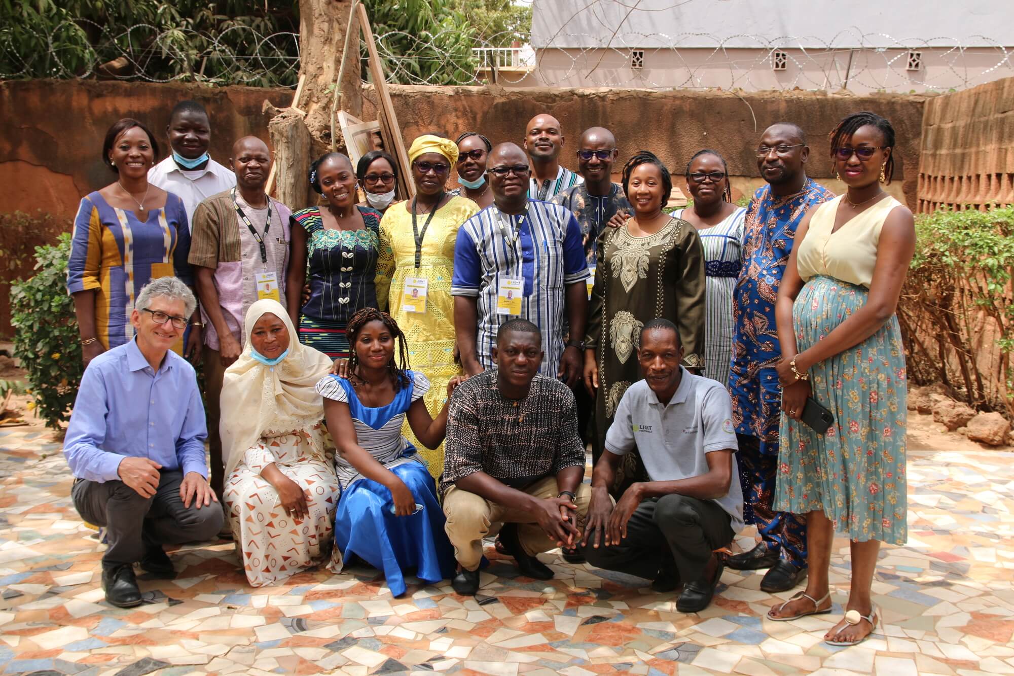 Das Team von Licht für die Welt in Burkina Faso steht im Hof des Büros und lächelt in die Kamera.