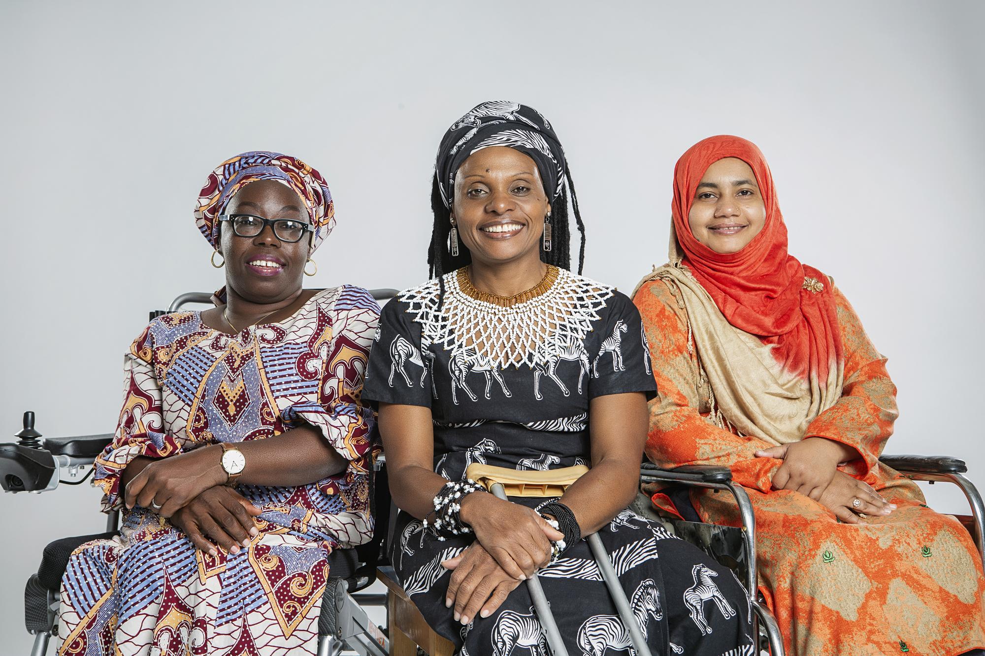 three women in national clothing look into the camera, smiling