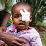 Der kleine Abdul aus Tansania hatte Grünen Star und wurde gerade operiert. Er sitzt in einem rosagemusterten Shirt und schaut neugierig in die Kamera.