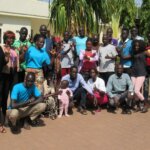 Jene Gruppe Menschen, die im Südsudan an einem Lexikon für Gebärdensprache gearbeitet hat, steht in einer Gruppe zusammen und lächelt in die Kamera.