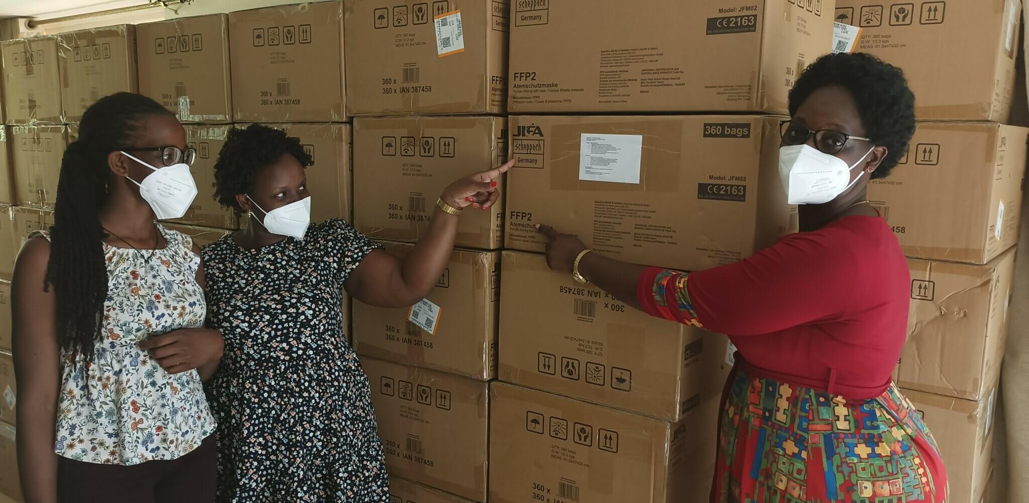 Das Team in Uganda steht vor Kartons mit FFP2-Masken der Scheppach GmbH