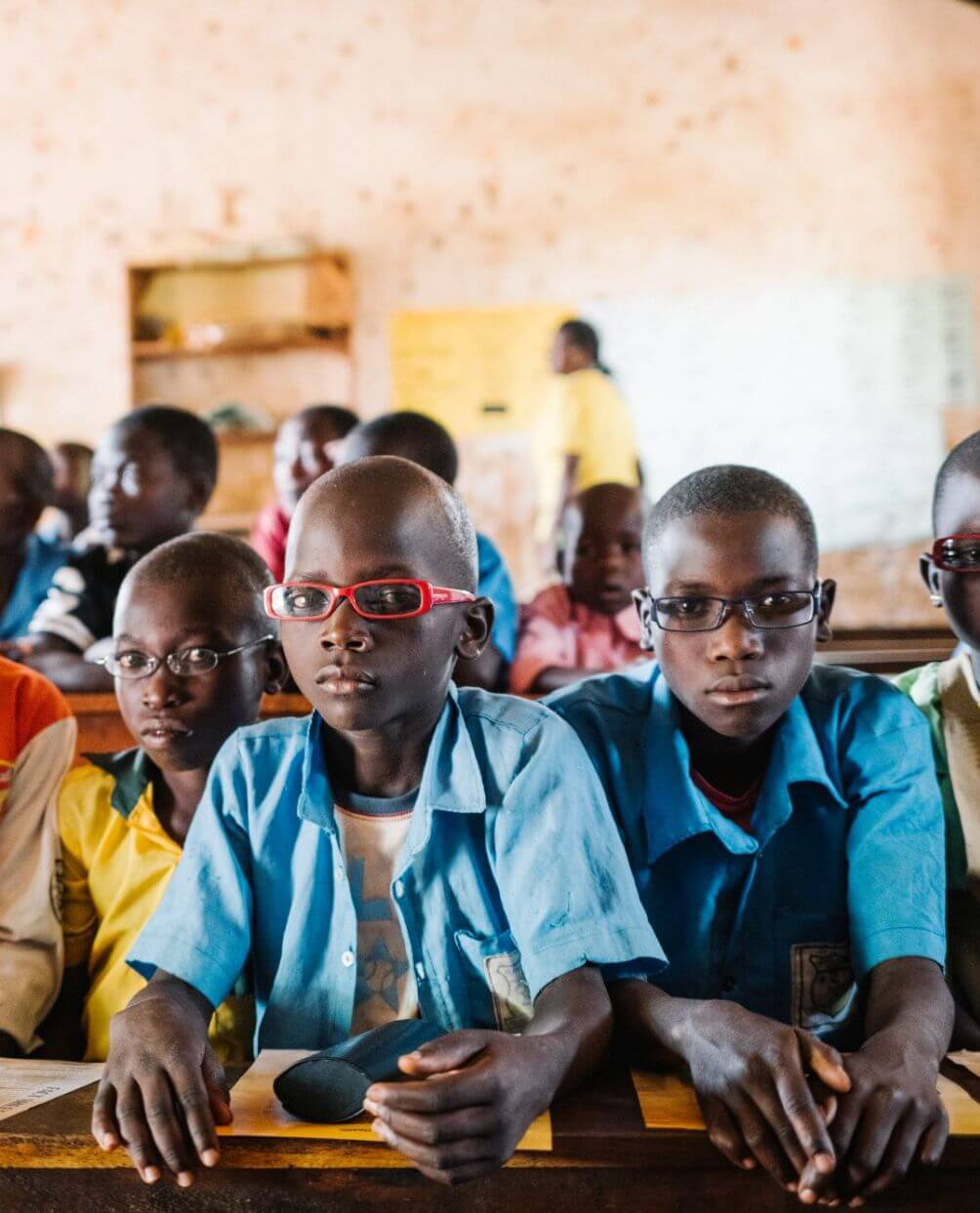 Ein Klassenzimmer in Hoima, Uganda. Die Schülerinnen und Schüler in der ersten Reihe tragen individuell angepasste Brillen.