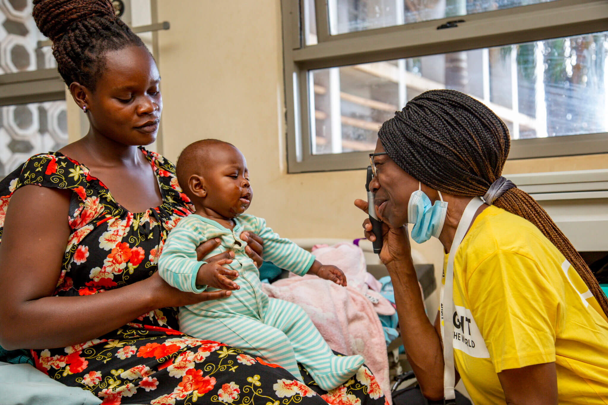 Dr. Mary Asiyo-Vogel unterhält sich mit einer jungen Mutter und untersucht die Augen des Babys.
