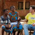 Der österreichische Arzt Philip Überbacher gibt einer Frau aus Mosambik einen Handschlag. Beide lachen.
