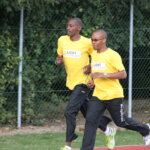 Henry Wanyoike läuft einen Spendenmarathon für Licht für die Welt. Er trägt ein gelbes T-Shirt und schwarze Sporthosen. Ein Kollege läuft neben ihm.