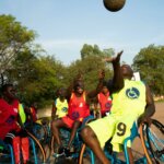 Die Teams beim Rolstuhlbasketball im Kampf um den Ball, während dieser durch die Luft geworfen wird.