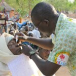 Bei einem mobilen Hilfseinsatz in Burkina Faso tropft ein augenmedizinischer Mitarbeiter einer Frau Medizin ins Auge.