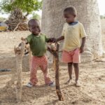zwei kleine lächelnde Jungen beim Spielen mit Baumstöcken und Baumstämmen