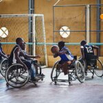 A group of six young individuals are playing basketball. One of them is passing the ball to the other person.