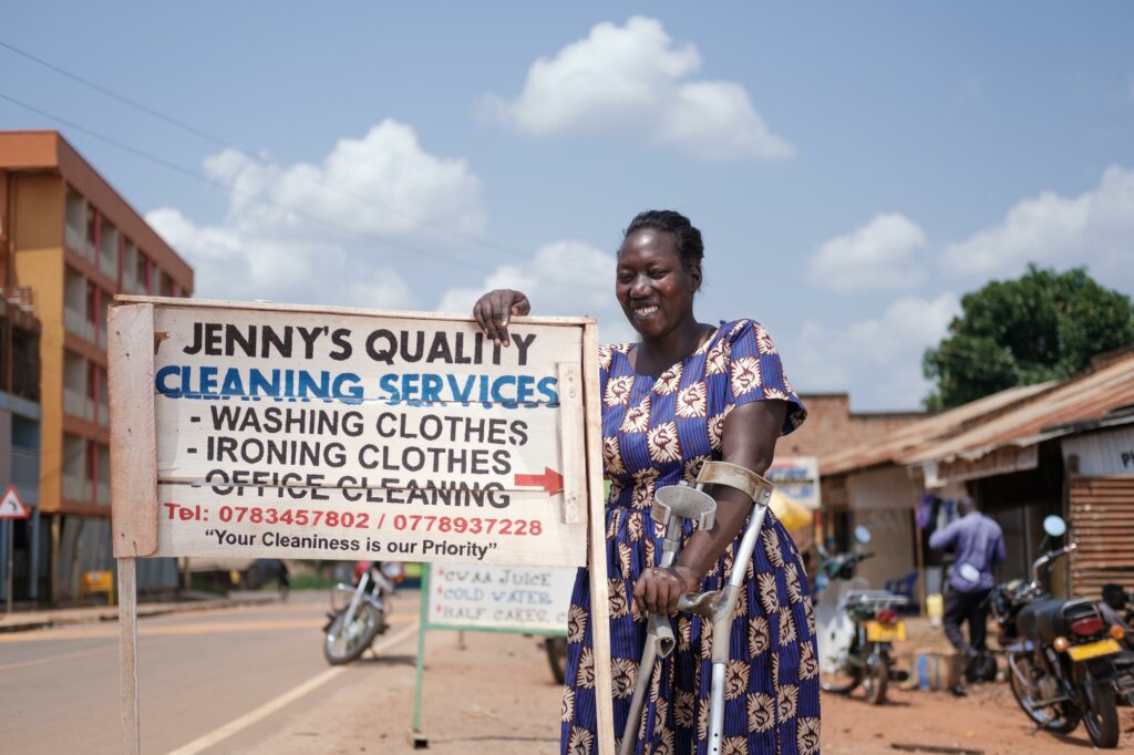 A woman in a blue patterned dress stands with a sign: 