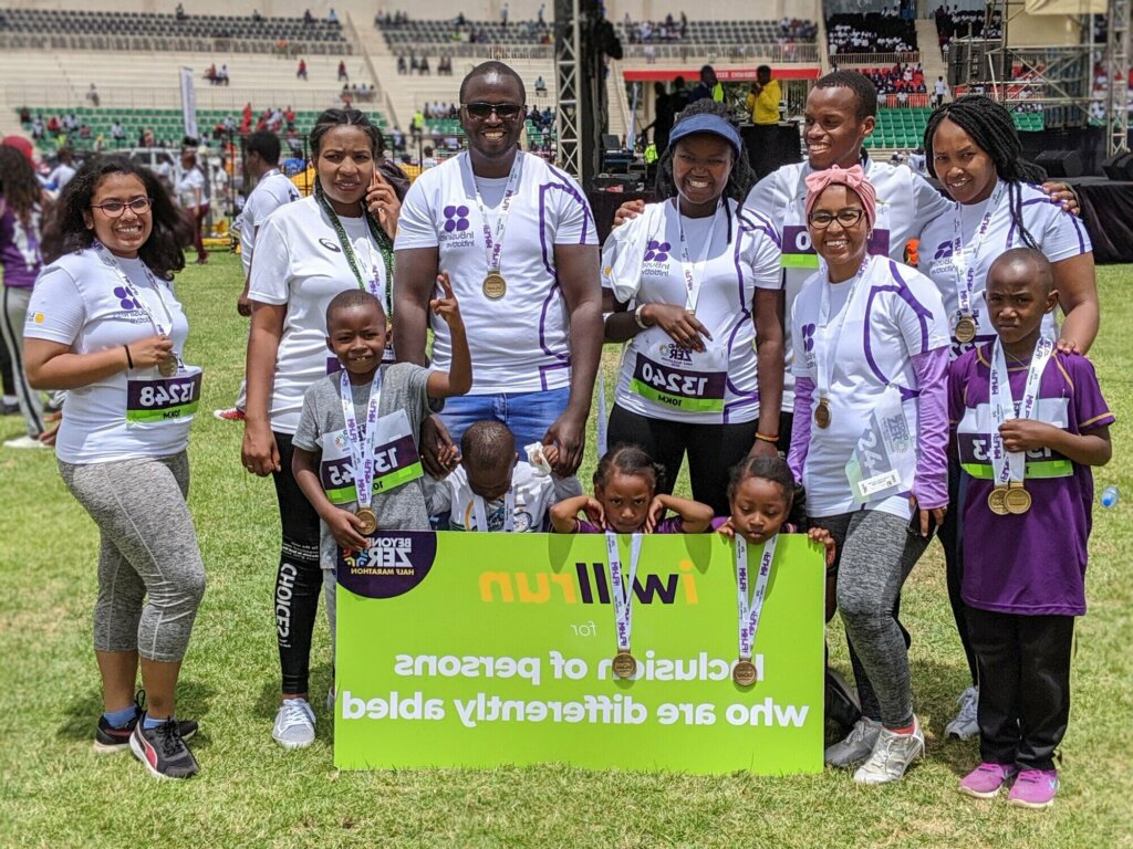 Light for the World Kenya team members, in running gear and with a sign saying 