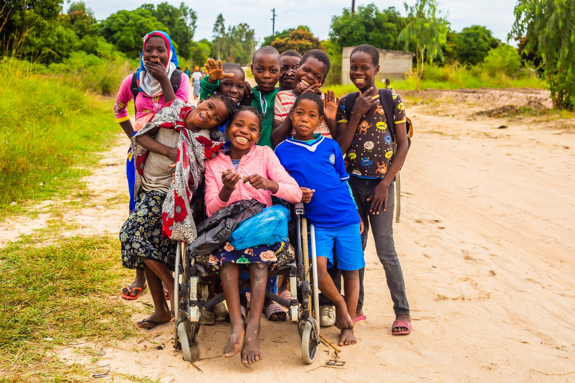 A slideshow image shows a big group of children with and without disabilities are coming together for a picture posing and smiling for the picture.