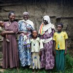 Eine sechsköpfige Familie steht zusammen. Die drei erwachsenen Frauen tragen lange Kleider und schauen sich glücklich an. Eine von ihnen trägt eine Augenbinde von ihrer vergangenen Operation.