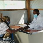 Doctor talking to his patient and reaching for something the woman is handing to him