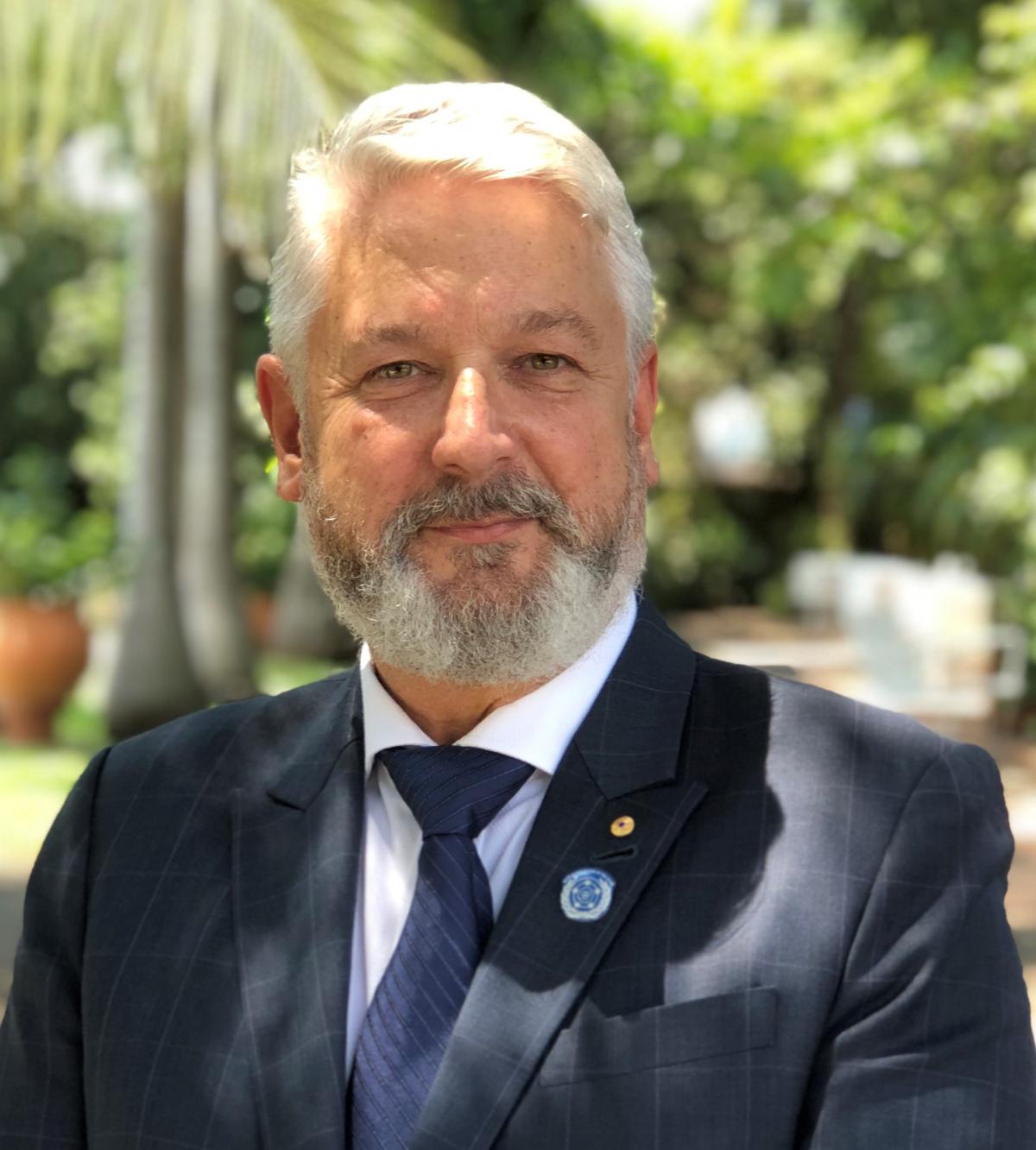 portrait Colin Allen, an Austrian white man with short white hair and a full white-gray beard wearing a dark suit and tie.