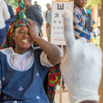 Lächelnde Frau beim Sehtest in Uganda