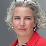 Joanna Conlon, a white British woman with curly gray hair in a red blazer