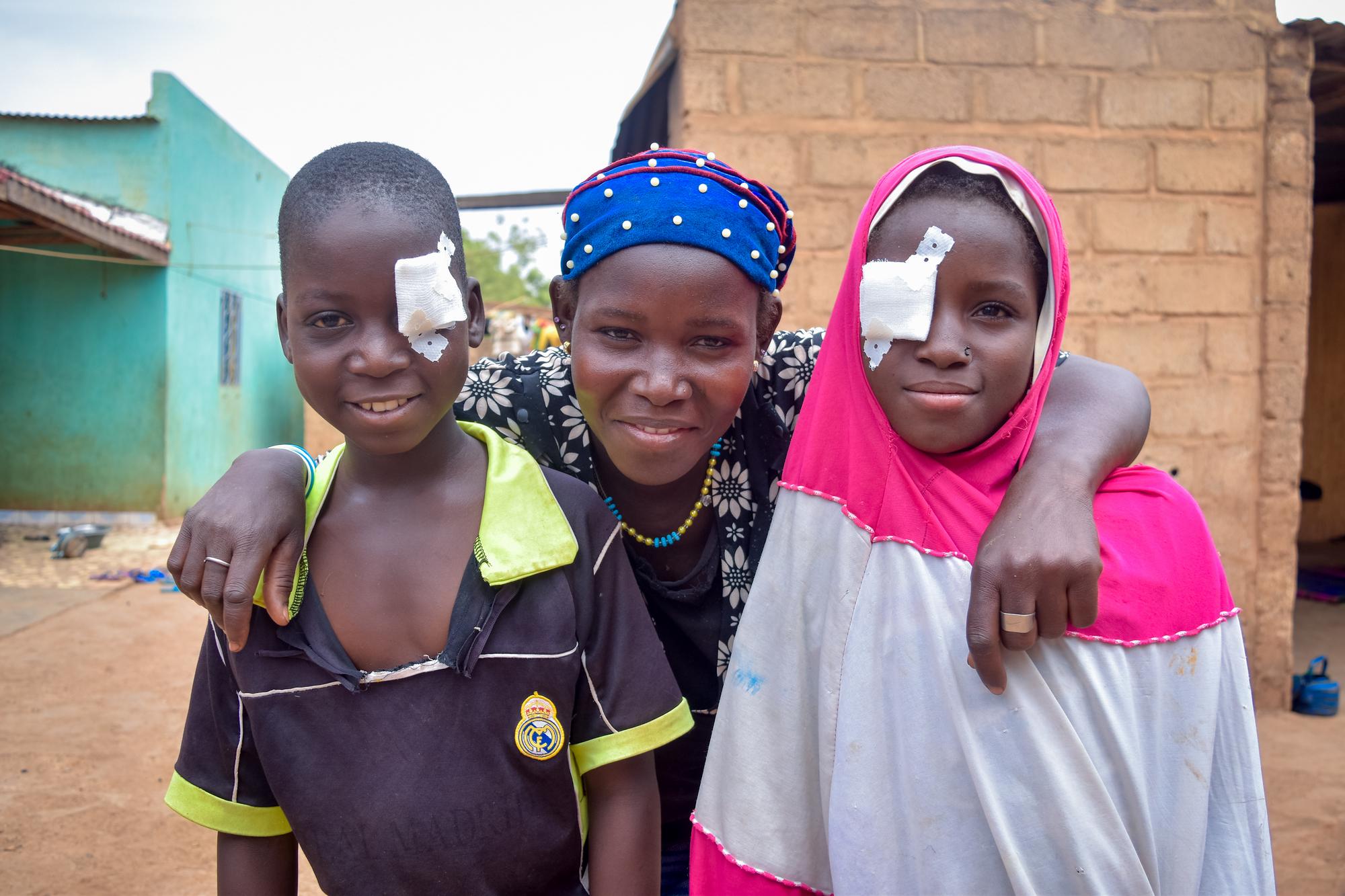 Oumou stands between her two children, Aboubacar, left, and Neimata, right, after their cataract surgeries