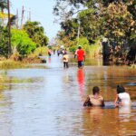 People struggle to walk through flooding