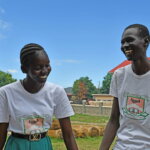 Two South Sudanese pupils smile as they pose for a photo outside their school. South Sudan signing the UNCRPD was one of the positive news stories of 2023.