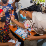 An ophthalmologist holds a blue torch towards the eye of a woman patient during eye care outreach in Mozambique.