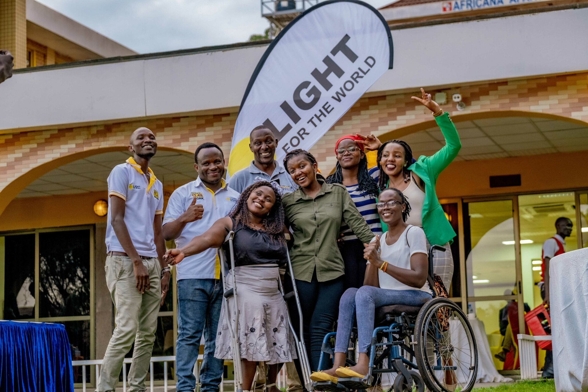 Several people, including Light for the World staff stand in front of a Light for the World banner smiling to celebrate the launch of We Can Work, one of the good news stories of 2023.