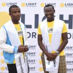 Image of two graduates from the Employable programme in front of a Light for the World banner. On the right is Brian Ngugi, who studies Building Technology at Machakos Technical Institute for the Blind in Kenya.