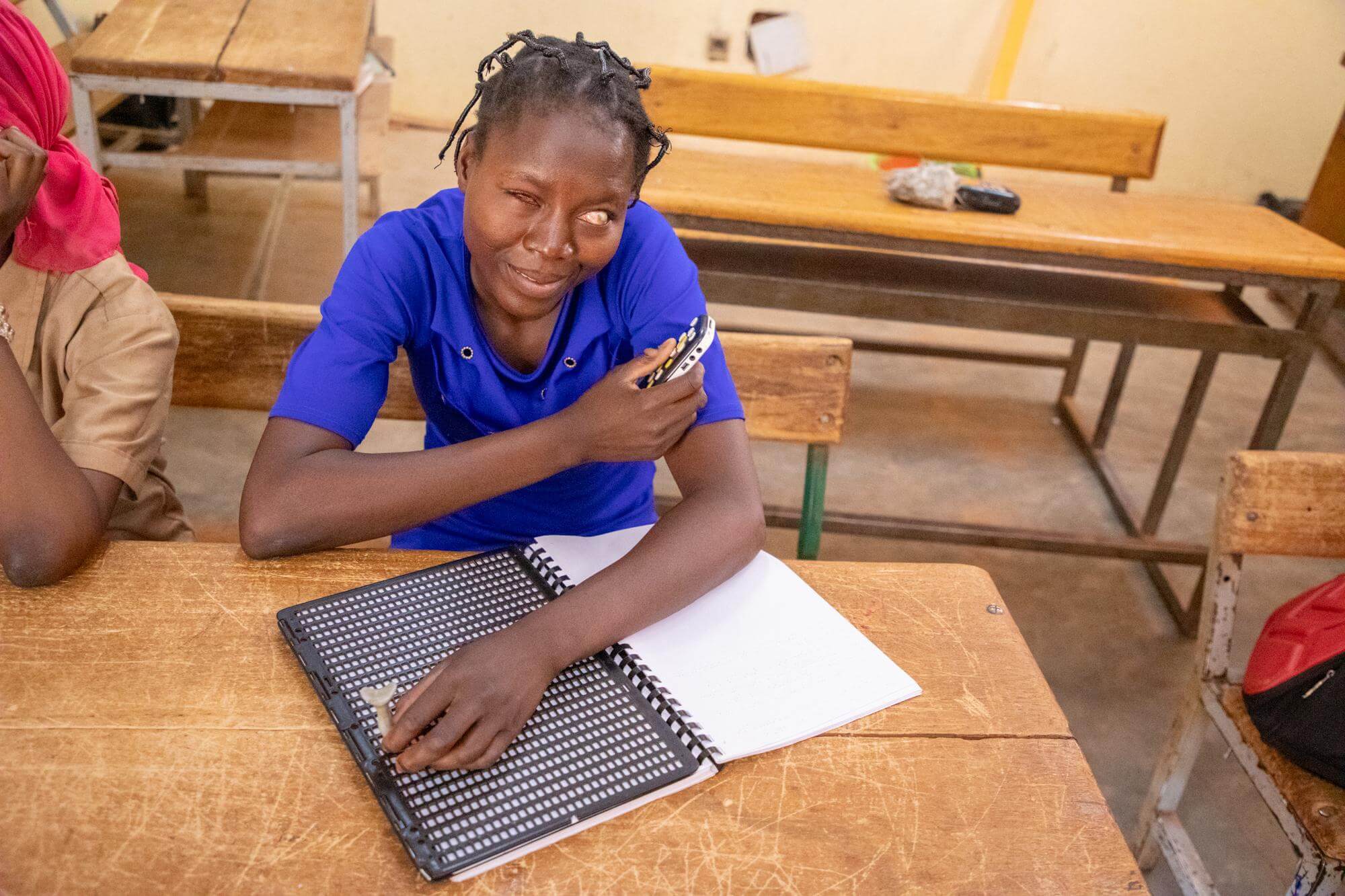 Image of Nadège, a student in a classroom in Burkina Faso, using an Evo10 Daisy recorder/player to record lessons and later transcribe them to braille. She wants to become a journalist.
