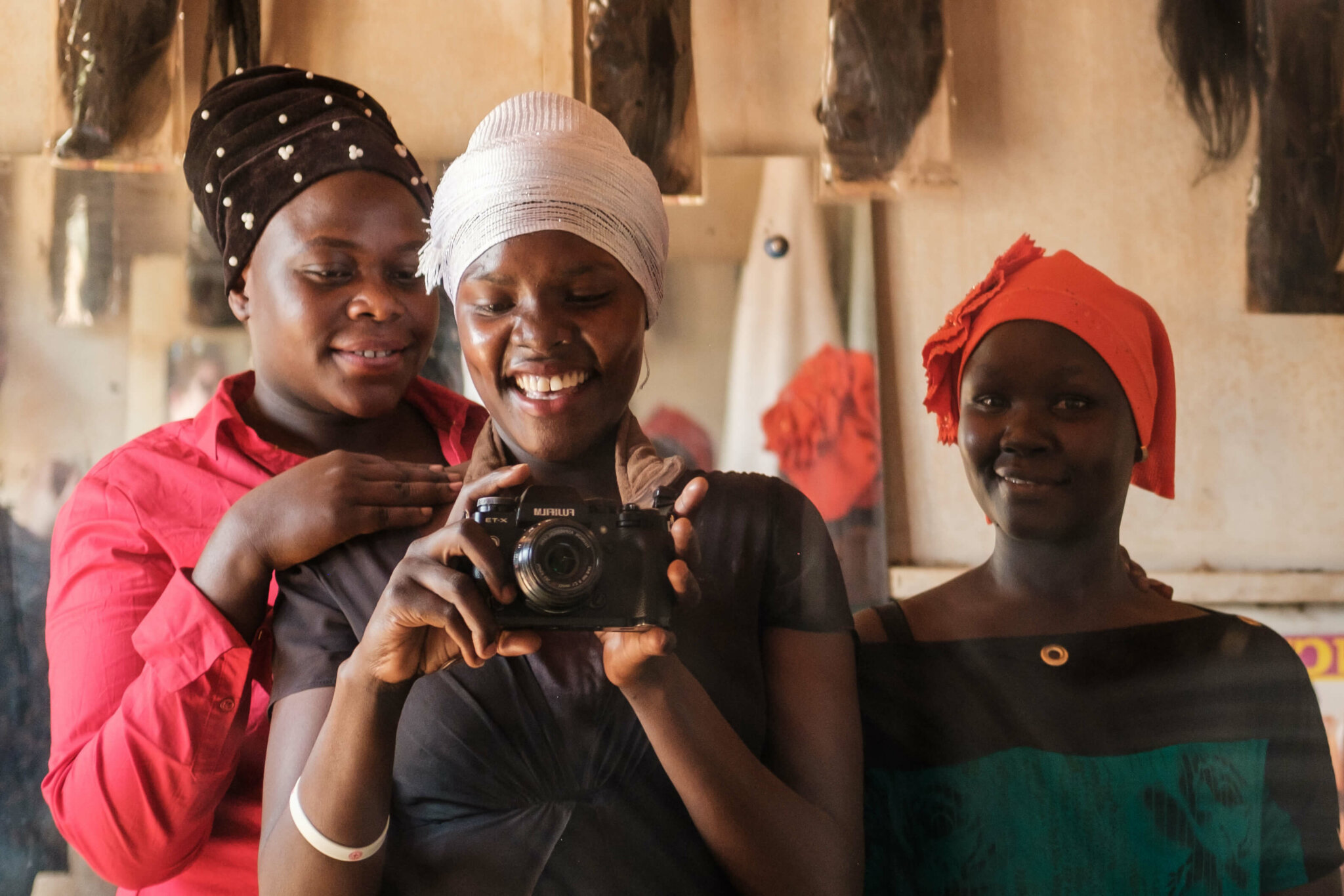 Image of three women who participated in the project: Overcoming Barriers to Food Security: A photo narrative by people with disabilities. The woman in the middle of the three holds a camera.