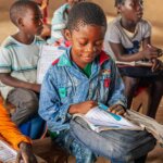 Image of Abel Nelson Manuel, a seven-year-old boy with cerebral palsy, looking at a book in a classroom. Abel received rehabilitation from AMAVIDA, a local partner of Light for the World in Mozambique. In an example of inclusive education, he now attends school and learns with other children his age. Copyright for the photo is Ulrich Eigner / Light for the World