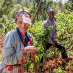 A woman smiles in a field, wearing a bandage over one eye. Restoring vision loss can help provide food security, one of the sustainable development goals.