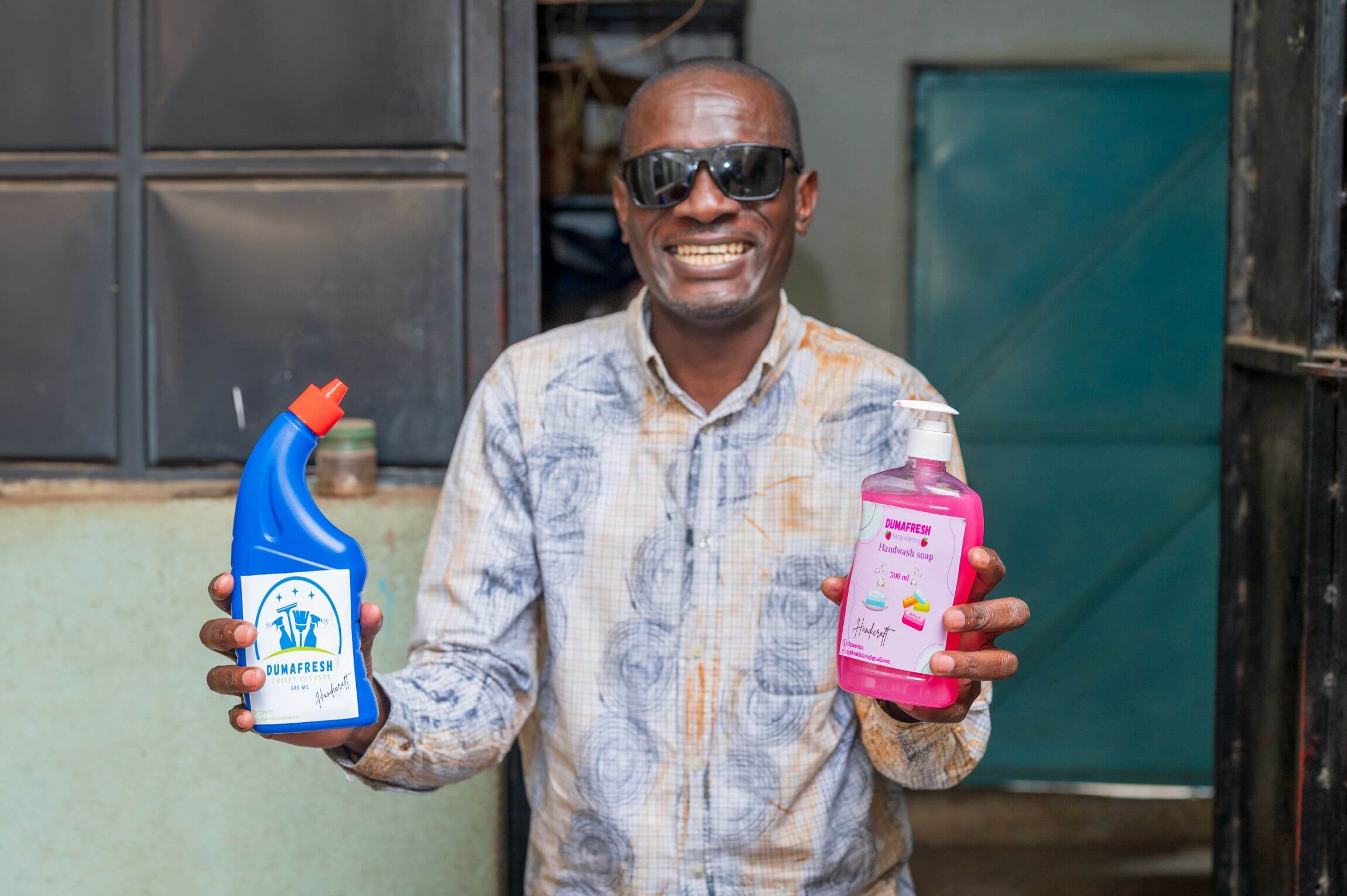 Hilton Nyambua, who runs Duma Fresh Enterprises, showing two of his products. He is smiling and holding them out to the camera. 