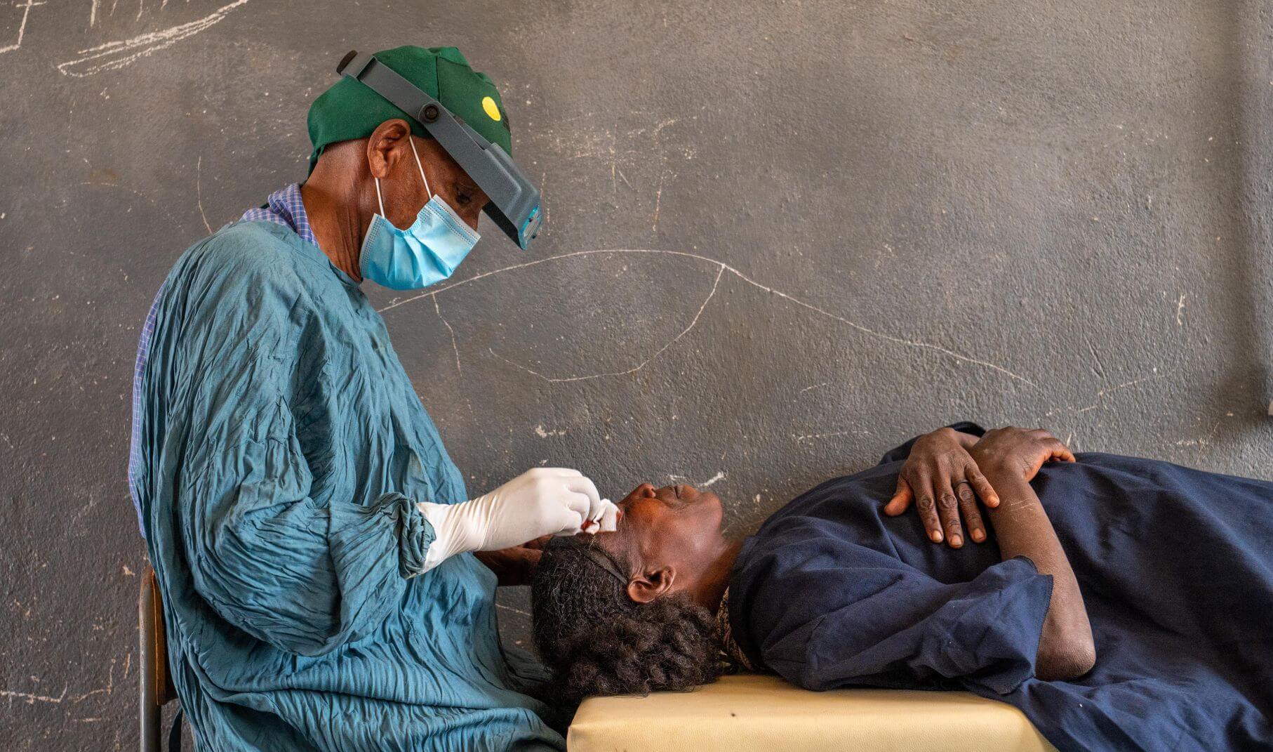 Hagos Beyene, lead surgeon and optometrist at Axum Saint Mary’s Comprehensive Hospital in Ethiopia, performs an eye procedure on a patient lying on an examination table.