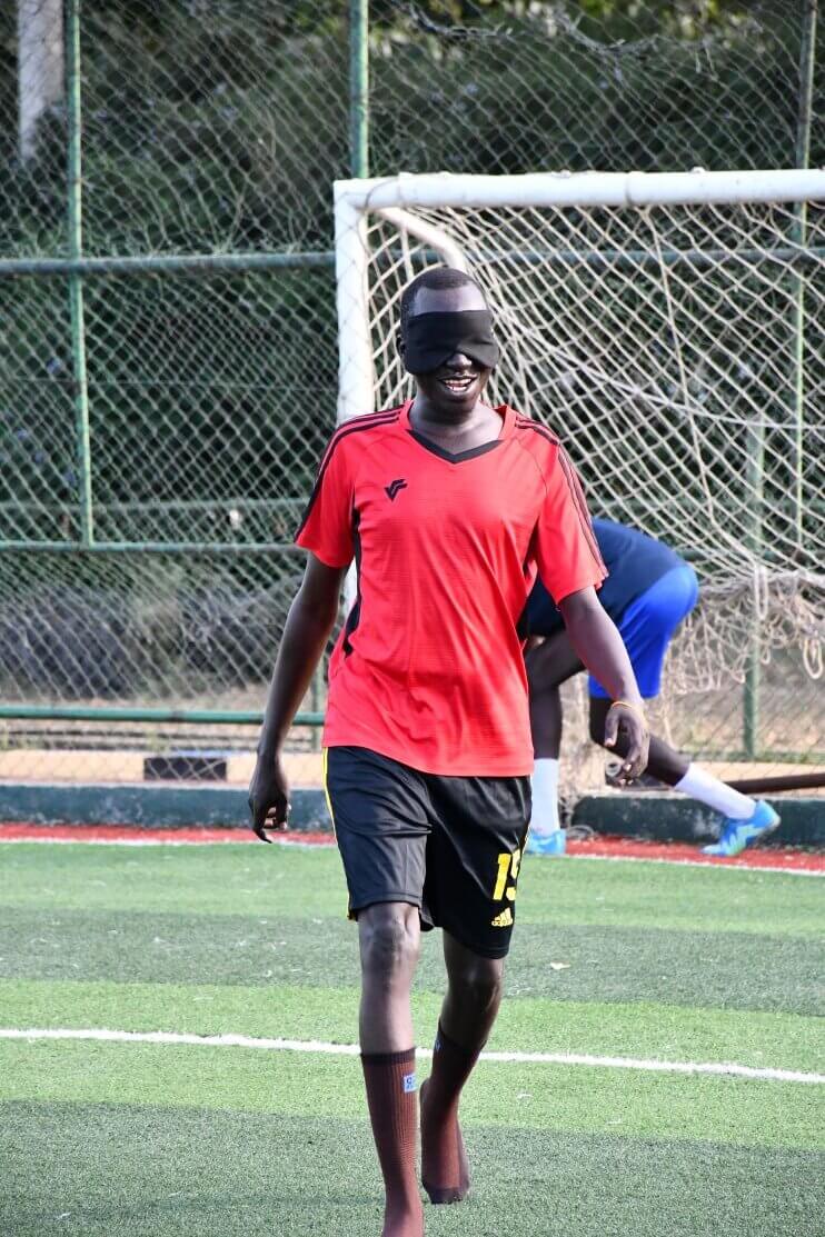 A blind football player stands near goalposts during practice. The player is part of South Sudan’s national blind football team.