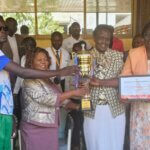 South Sudan blind football team captain Martin Ladu Paul touches the golden trophy from African Blind Football Championship. Next to him, also touching the trophy, are three women including the Undersecretary in the Ministry of Youth and Sports and vice president Rebecca Nyandeng.