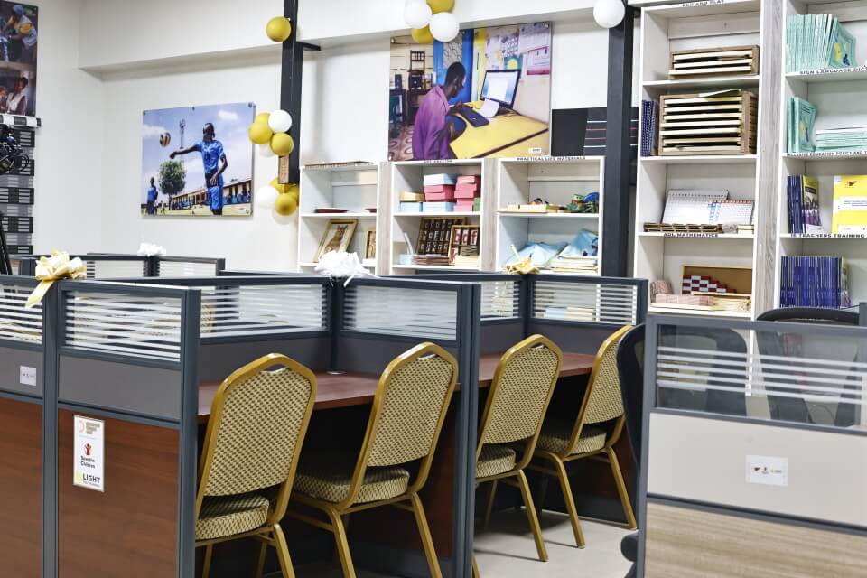 Inside of the Disability Inclusive Resource Centre at the University of Juba. There are three desks with chairs behind them and shelves containing  adapted learning materials.