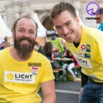 Thomas Geierspichler und Andi Onea lachen mit einem Licht für die Welt T-Shirt in die Kamera.