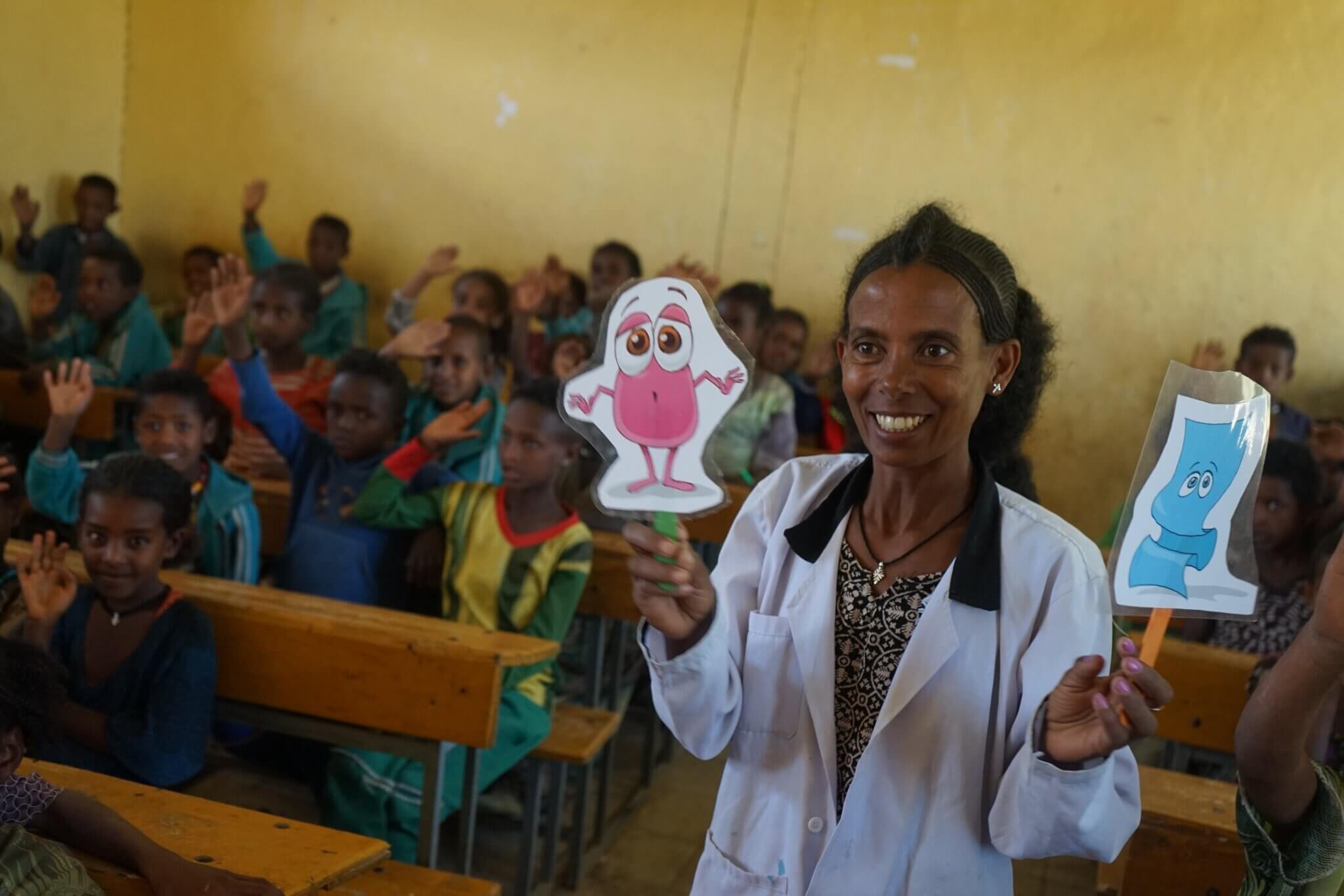 Äthiopische Augenärztin, die Schulkinder über Hygiene und Trachom aufklärt. Sie hält eine Zeichentrickfigur in der Hand.